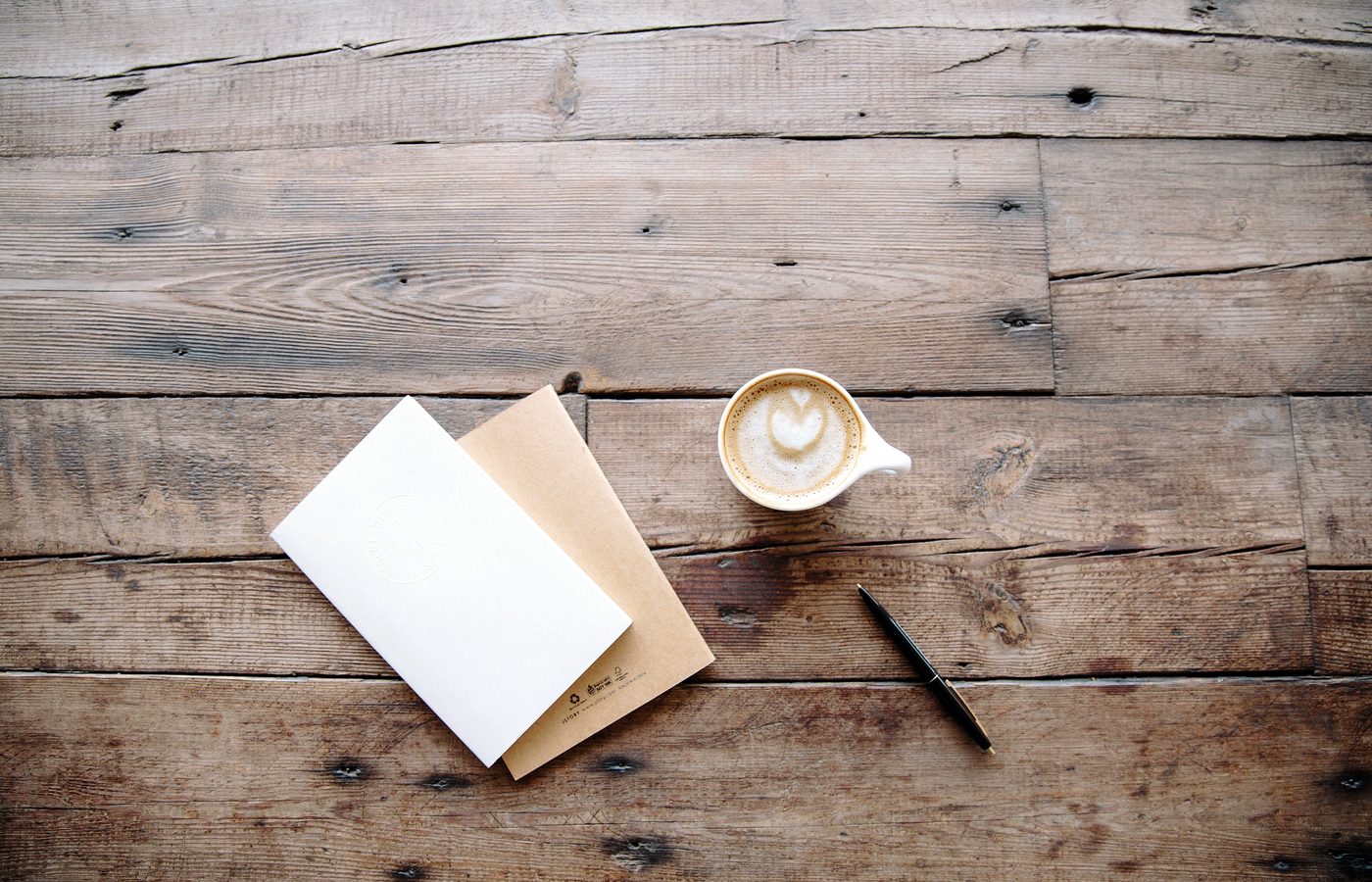 Carnet ouvert et crayon posés sur une table de travail